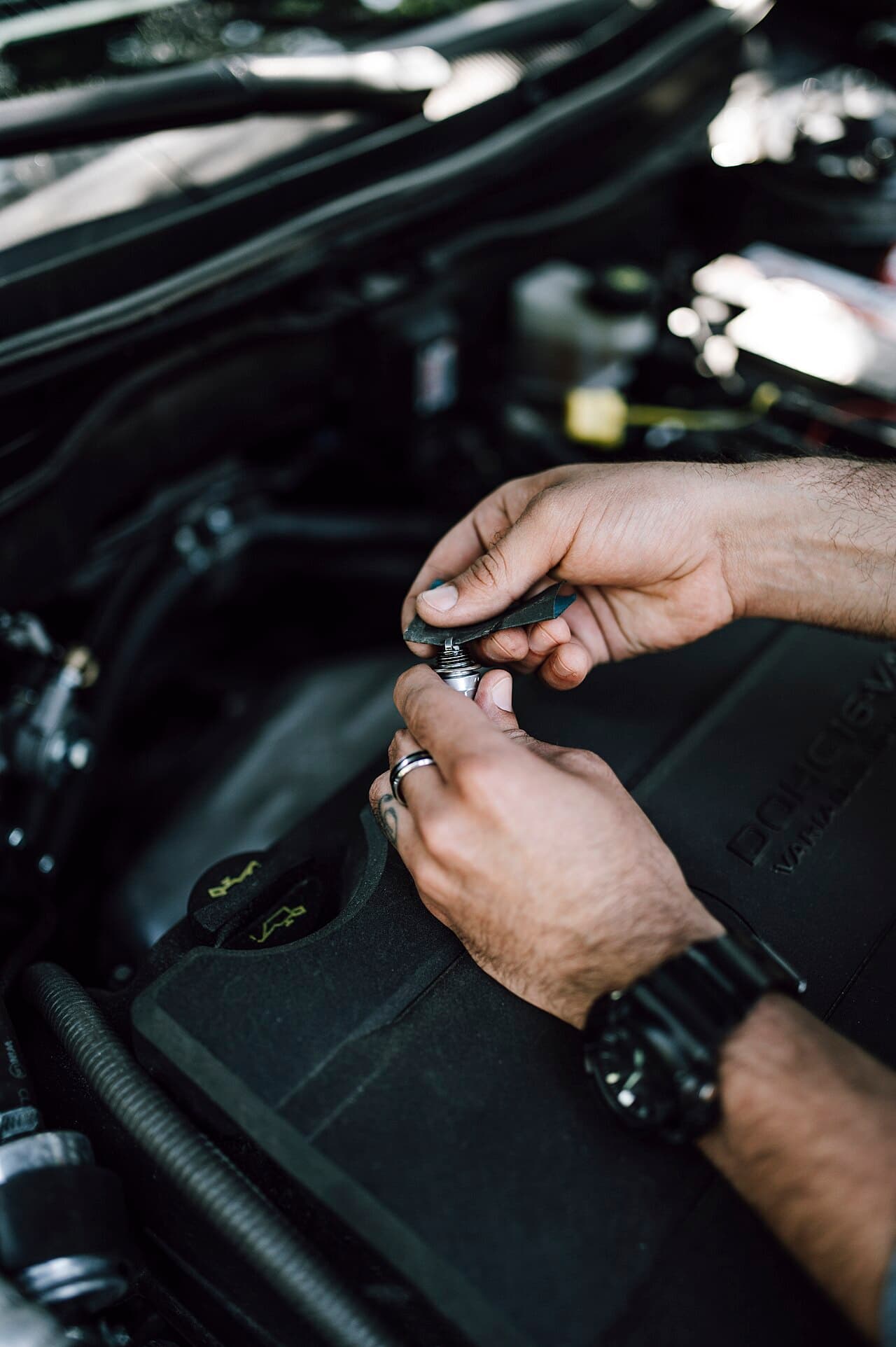 Mechanic inspecting and adjusting car engine parts under the hood